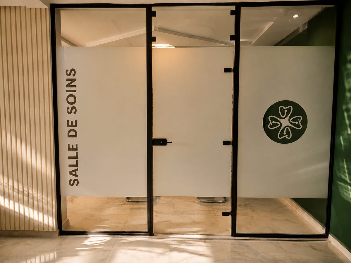 Porte vitrée de la salle de soins portant le logo du cabinet